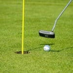 Der Putter schlägt den Ball ins Loch